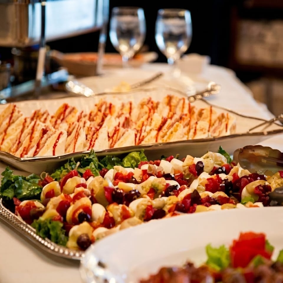 Restaurant buffet featuring colorful salad, assorted appetizers, and rows of breadsticks on a white-clothed table.